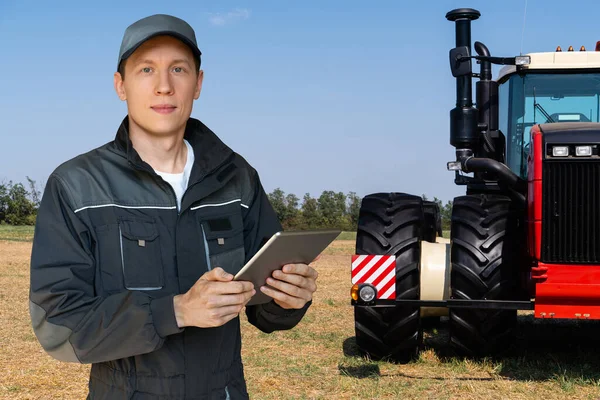 Farmer with a digital tablet on the background of an agricultural tractor