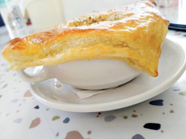 Bir parça Zuppa-Zuppa, bir fincan kahve ve ahşap arka planda beyaz bir tabak.