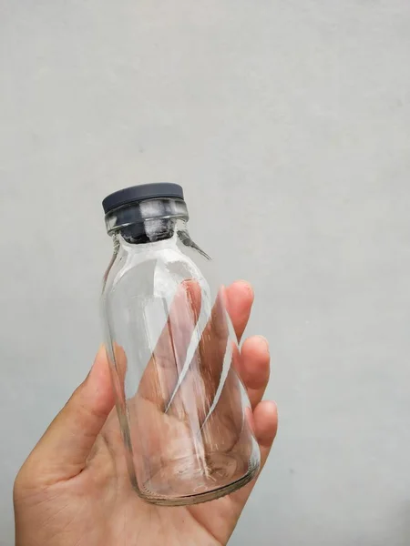 Close Hand Empty Glass Jar White Plastic Bottle Water Grey — Stockfoto