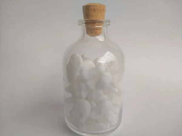 Белые Камни Блестящей Стеклянной Бутылке Деревянной Крышкой Белом Фоне — стоковое фото