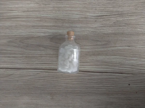 木製のテーブルの上に木製の蓋付き光沢のあるガラス瓶の白い石 — ストック写真