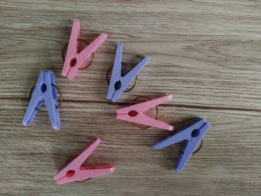 Ahşap arka planda pembe ve mor mandallar.