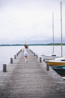 Genç kadın gölün yakınındaki iskelede oturuyor.