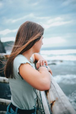 Elleriyle iskelede duran genç ve güzel bir kadın.