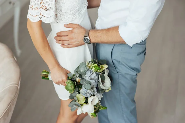 Крупный план рук молодоженов со свадебным букетом — стоковое фото