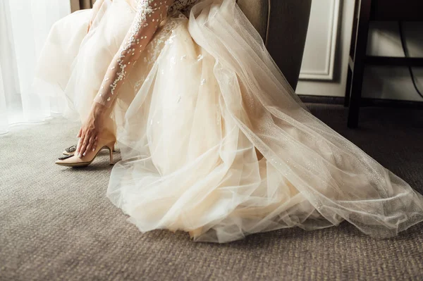 Menyasszony csipke ruha felveszi az esküvői cipőt, és kiegyenesíti őket a kezével — Stock Fotó