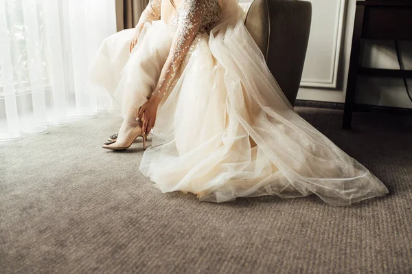 Bride with lace dress puts on her wedding shoes and straightens them with her hand — Stock Photo, Image