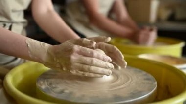 Seramik fincanın yakın plan çekimi çömlek çarkında dönüyor ve elleri kilde şekilleniyor.