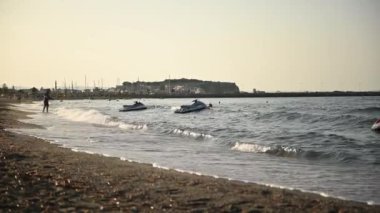 Güneş batarken Akdeniz 'in dalgalarında jet skiler yüzer.