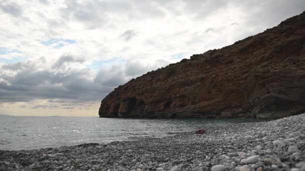 Μαζικές πέτρες βυθίζονται στο νερό σε μια παραλία με βότσαλα — Αρχείο Βίντεο