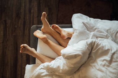 Genç heteroseksüel bir çiftin ayakları yatakta dinleniyor..