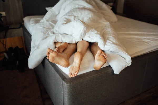 Die Füße eines jungen heterosexuellen Paares entspannen sich im Bett. — Stockfoto