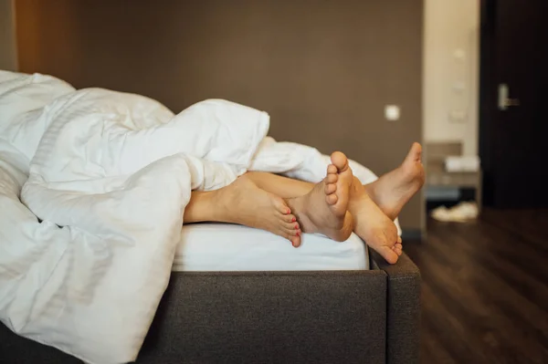 Picioarele unui cuplu heterosexual tânăr care se relaxează în pat. — Fotografie, imagine de stoc