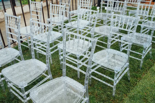White glass chairs stand on the green grass. Round arch for a wedding ceremony In the background . Raining day — Stock Photo, Image