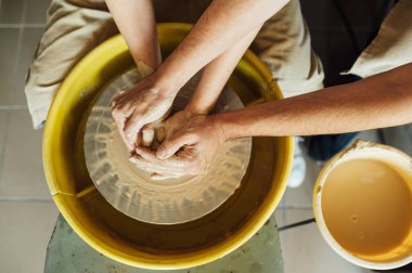Birbirine aşık bir çift çömlek atölyesinde ortak bir fincan yaratıyor. Potter çömlek çarkında seramik demlik yapıyor.