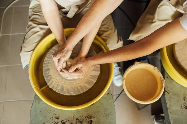 Egy szerelmes pár létrehoz egy közös csészét egy kerámia műhelyben. Fazekas kerámia edényt készít a kerámia keréken — Stock Fotó