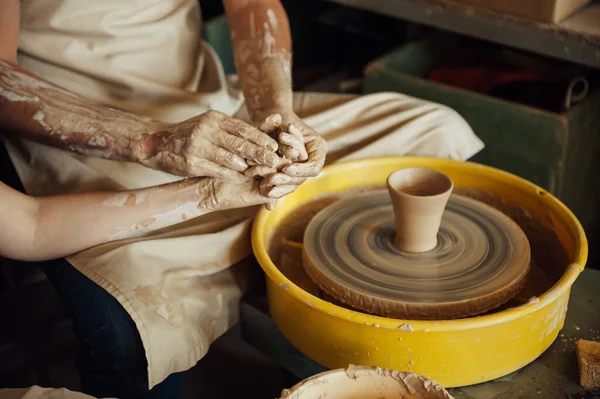 Una pareja enamorada crea una taza conjunta en un taller de cerámica. Potter haciendo olla de cerámica en la rueda de cerámica —  Fotos de Stock