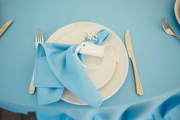 Свадебные столы для гостей. Круглые столы с голубой скатертью. Украшенные цветами, тарелками, стаканами и многим другим — стоковое фото