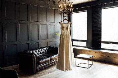 Düğünden önce gelinin beyaz elbisesi. Karanlık bir odada bulunuyor.