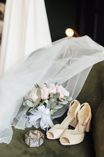 Esküvői csokor fehér bazsarózsa, cipő és jegygyűrűk egy fa háttér — Stock Fotó