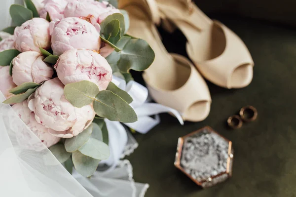 Bruiloft boeket van witte pioenen, schoenen en trouwringen op een houten achtergrond — Stockfoto