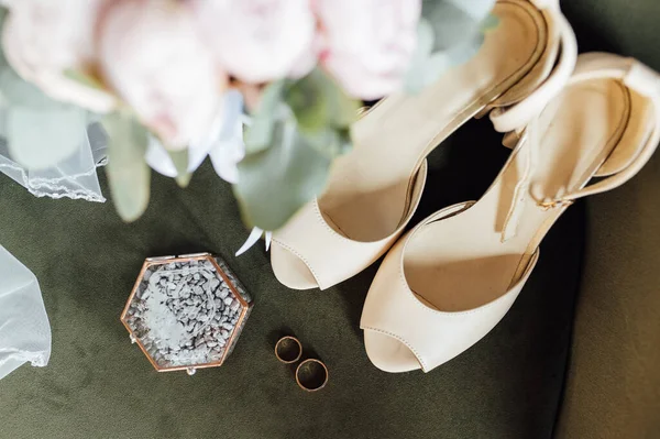 Esküvői csokor fehér bazsarózsa, cipő és jegygyűrűk egy fa háttér — Stock Fotó