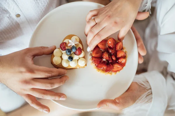Happy couple having breakfast in bed with delicious cookies with strawberries on top — Foto de Stock