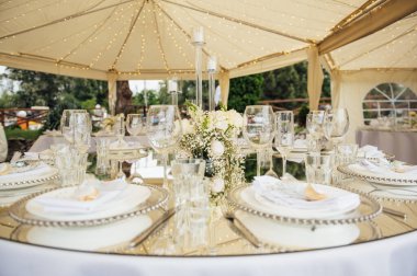 Lüks restoran. Lüks içecekler, beyaz masalar, misafirler için servis tabakları ve bardaklar.