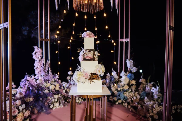 Arco de casamento bonito moderno com muitas flores e um grande bolo de casamento. — Fotografia de Stock