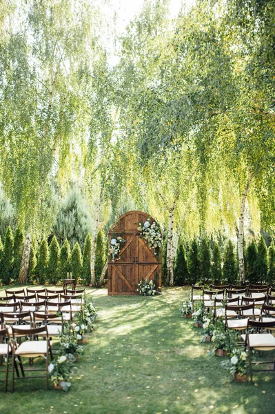 A beautiful area for an outdoor wedding ceremony. Arch Decorated with a large wooden door with many flowers. — Stock Photo, Image