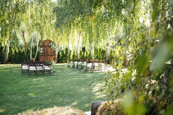 A beautiful area for an outdoor wedding ceremony. Arch Decorated with a large wooden door with many flowers. — Stock Photo, Image