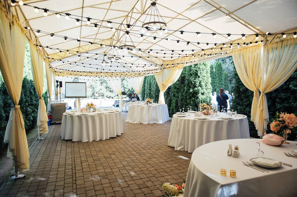 Evening decoration of a wedding party. Tables for guests with a garland and lamps