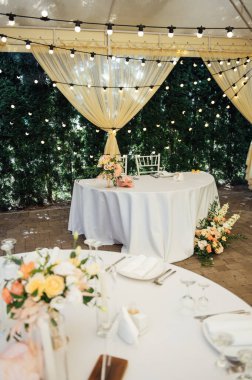 Bir düğün partisinin akşam dekorasyonu. Çiçekli ve lambalı konuklar için masalar