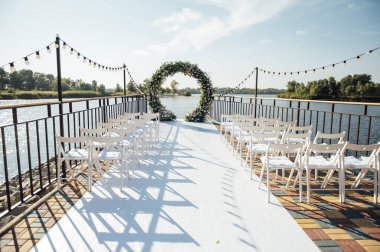 Beyaz çiçekler ve yeşilliklerle süslenmiş daire şeklinde düğün kemeri..