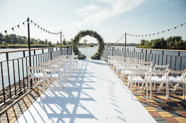 Beyaz çiçekler ve yeşilliklerle süslenmiş daire şeklinde düğün kemeri..