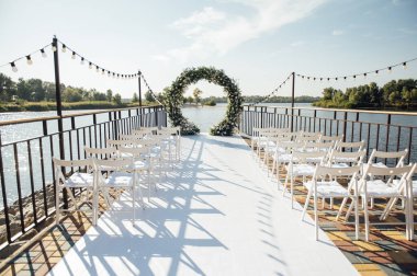 Beyaz çiçekler ve yeşilliklerle süslenmiş daire şeklinde düğün kemeri..