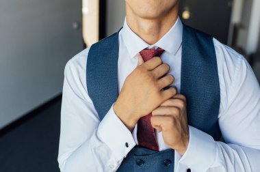 Mavi takım elbiseli genç işadamı kırmızı kravatını düzeltiyor.