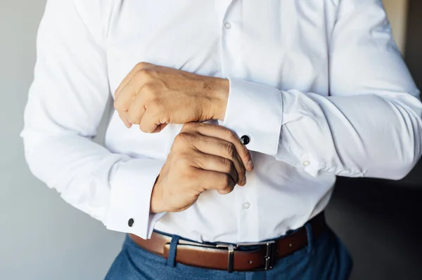 Homem de negócios jovem em um terno azul endireita um punho de punho em uma camisa branca — Fotografia de Stock