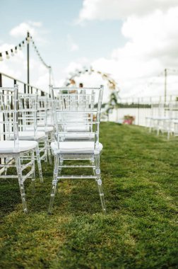 Nehir kenarında bir düğün merasimi için yuvarlak kemer. Beyaz cam sandalyeler misafirler için. Yakın çekim, kopyalama alanı, ayarlı. Davetiye, aşk konsepti