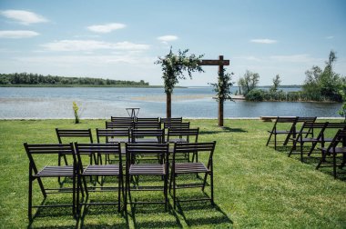 Arka planda düğün kemeri ve ahşap sandalyeler güzel nehirde. Çiçeklerle süslenmiş ahşap kemer..