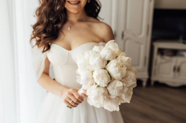 Gelin elinde bir buket beyaz şakayık tutuyor..