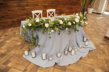 Yeni evliler için düğün başkanlığı, partideki düğün gününde. Taze çiçeklerle süslenmiş masa ve ahşap arka plan..