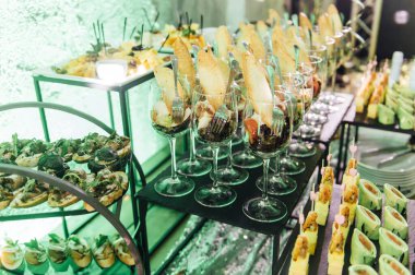 Yaratıcı disko ışıklandırması olan bir partide farklı tipte abur cuburlarla dolu büyük bir masa. Çeşitli atıştırmalıklar, et, bardakta meyve ve daha fazlası..