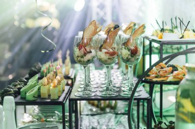 Yaratıcı disko ışıklandırması olan bir partide farklı tipte abur cuburlarla dolu büyük bir masa. Çeşitli atıştırmalıklar, et, bardakta meyve ve daha fazlası..