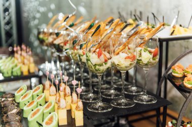 Yaratıcı disko ışıklandırması olan bir partide farklı tipte abur cuburlarla dolu büyük bir masa. Çeşitli atıştırmalıklar, et, bardakta meyve ve daha fazlası..