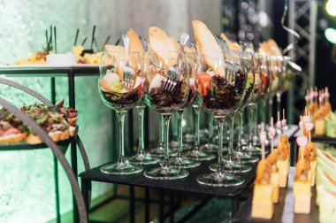 Yaratıcı disko ışıklandırması olan bir partide farklı tipte abur cuburlarla dolu büyük bir masa. Çeşitli atıştırmalıklar, et, bardakta meyve ve daha fazlası..