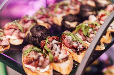 Yaratıcı disko ışıklandırması olan bir partide farklı tipte abur cuburlarla dolu büyük bir masa. Çeşitli atıştırmalıklar, et, bardakta meyve ve daha fazlası..