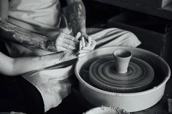 A couple in love creates a joint cup in a pottery workshop. Potter making ceramic pot on the pottery wheel.