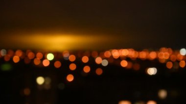 Gece şehrinin bulanık görüntüsü. Akşam ışıkları gökyüzünü aydınlatıyor. Soyut parlak bulanık renkli bokeh. Şehir arka planında Bokeh ışıkları