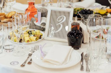 Lüks restoran. Lüks içecekler, beyaz masalar, misafirler için servis tabakları ve bardaklar..